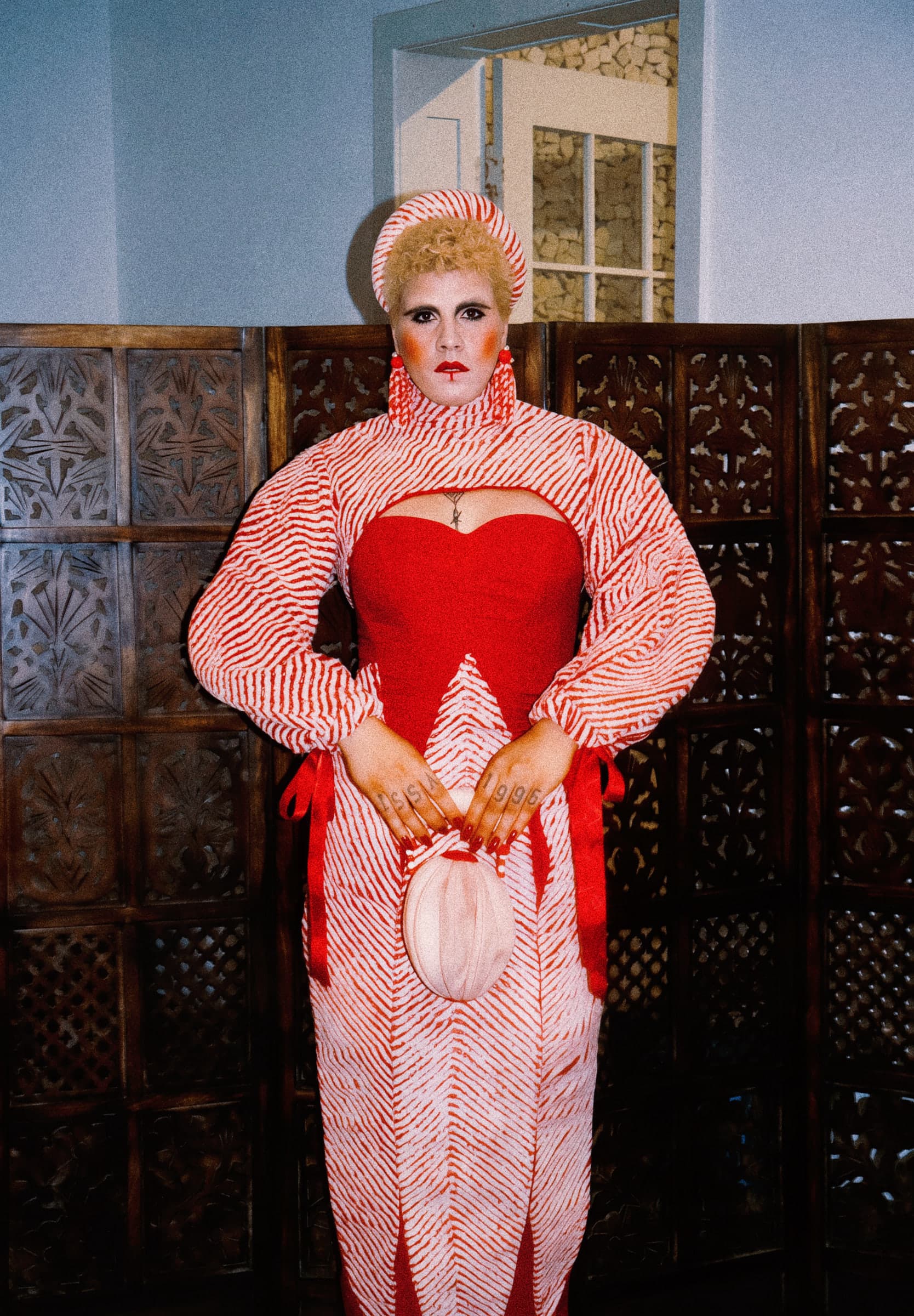 Registro próprio de corpo inteiro, com vestido vermelho, painéis listrados e acessório oval.